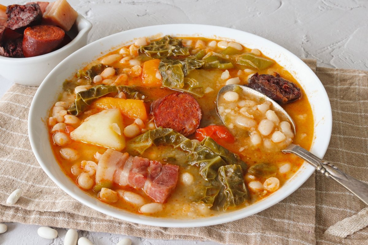 Mesa de menú del día casero servida en un mesón tradicional cántabro, varios platos a la vista, luz natural de mediodía.