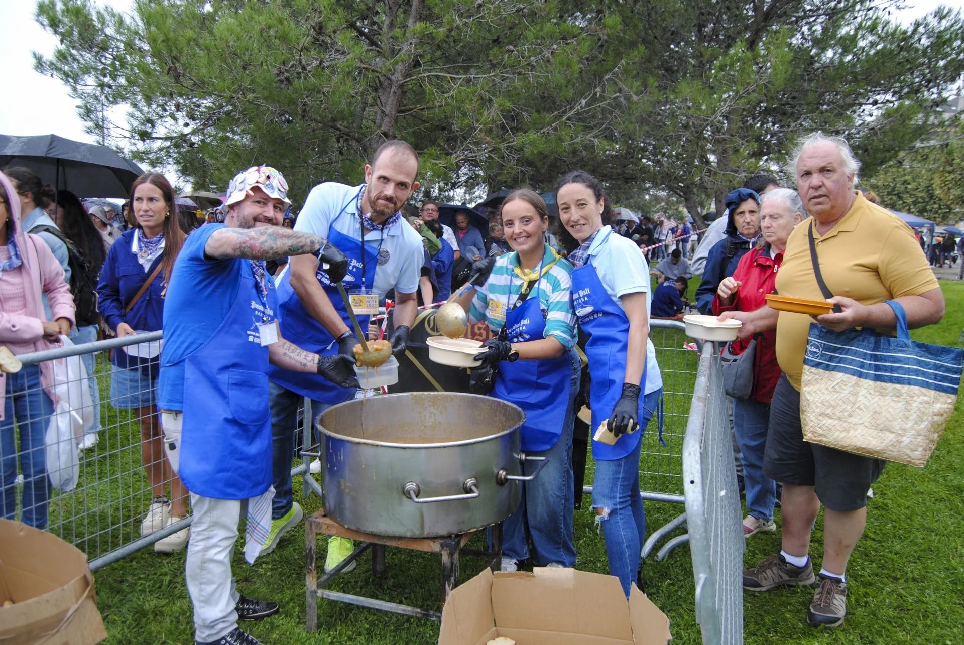 Grandes calderos de guiso marinero servidos al aire libre durante una fiesta popular