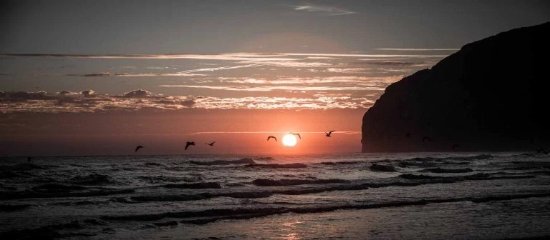 Playa de Berria en Santoña al atardecer, marea baja, siluetas paseando por la arena con Monte Buciero al fondo