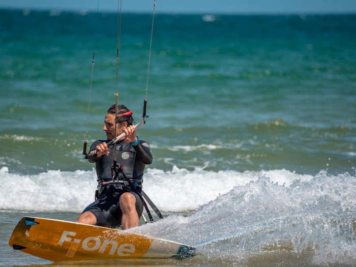 Vista general de la playa de Ris y Trengandín en Noja con velas de windsurf o kitesurf en el agua, tarde de verano