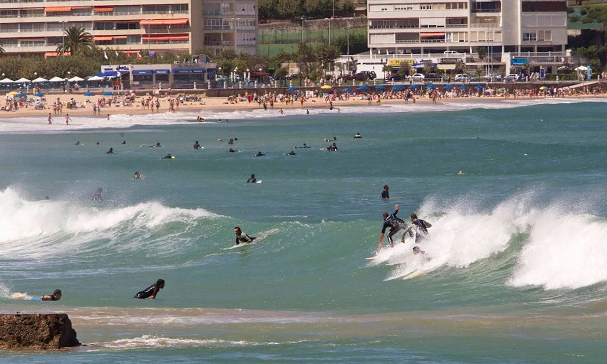 Surfistas entrando al agua frente a la Primera Playa del Sardinero al atardecer