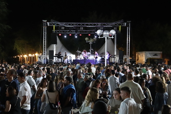 Ambiente de verbena popular de pueblo por la noche, luces de feria y gente bailando en una plaza cántabra