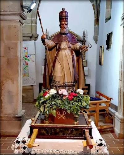 Procesión religiosa saliendo de una ermita rural en Cantabria, gente del pueblo acompañando la imagen del santo bajo palio