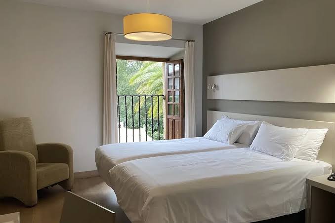 Habitación de hotel estándar con desayuno servido en bandeja, luz de mañana entrando por la ventana