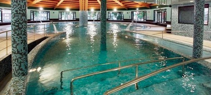 Vista general de una piscina termal exterior en un balneario de montana en Cantabria, vapor sobre el agua en una manana fresca de verano