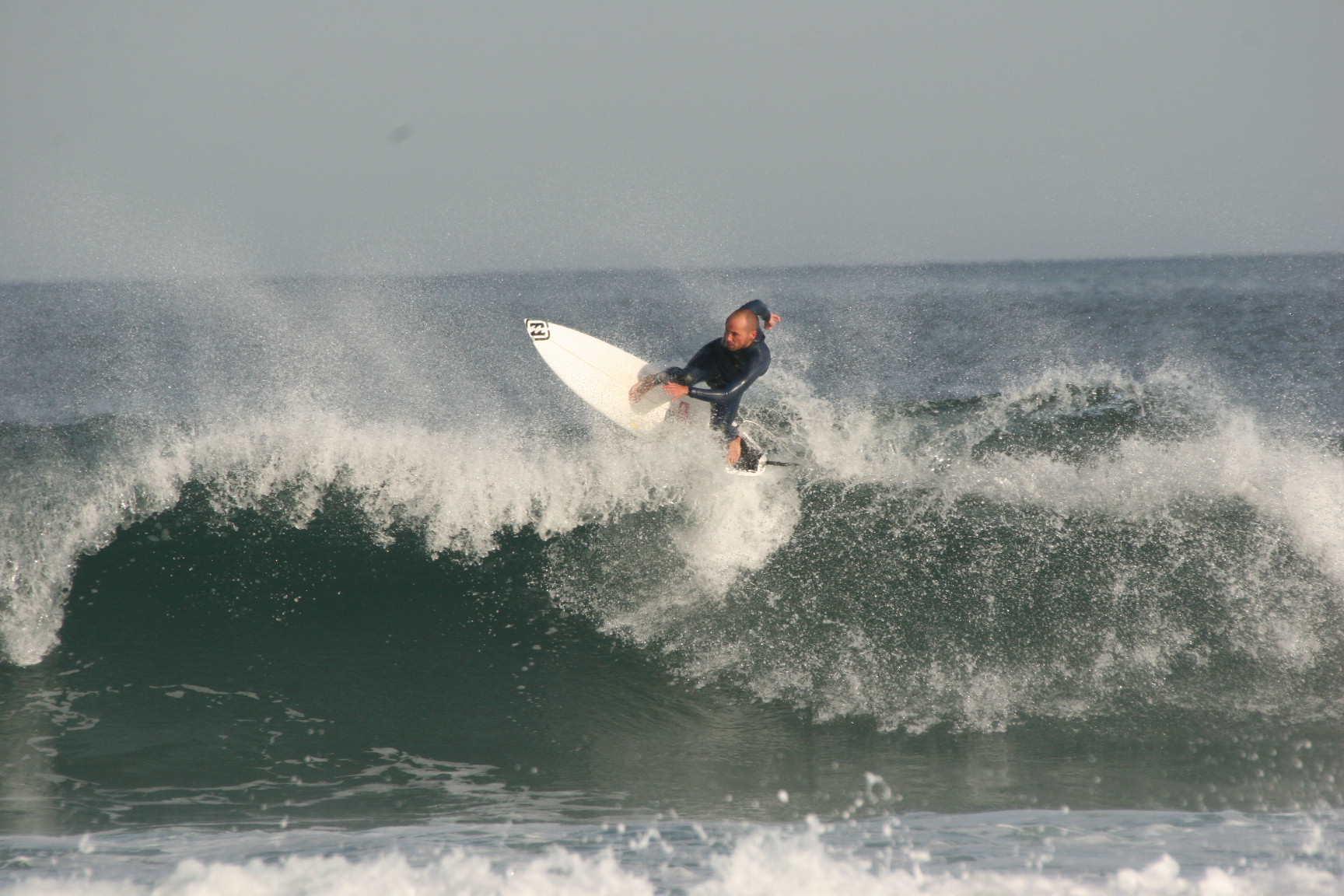 Surfistas entrando al agua en la Playa del Puntal con oleaje abierto al Cantábrico, tarde de otoño