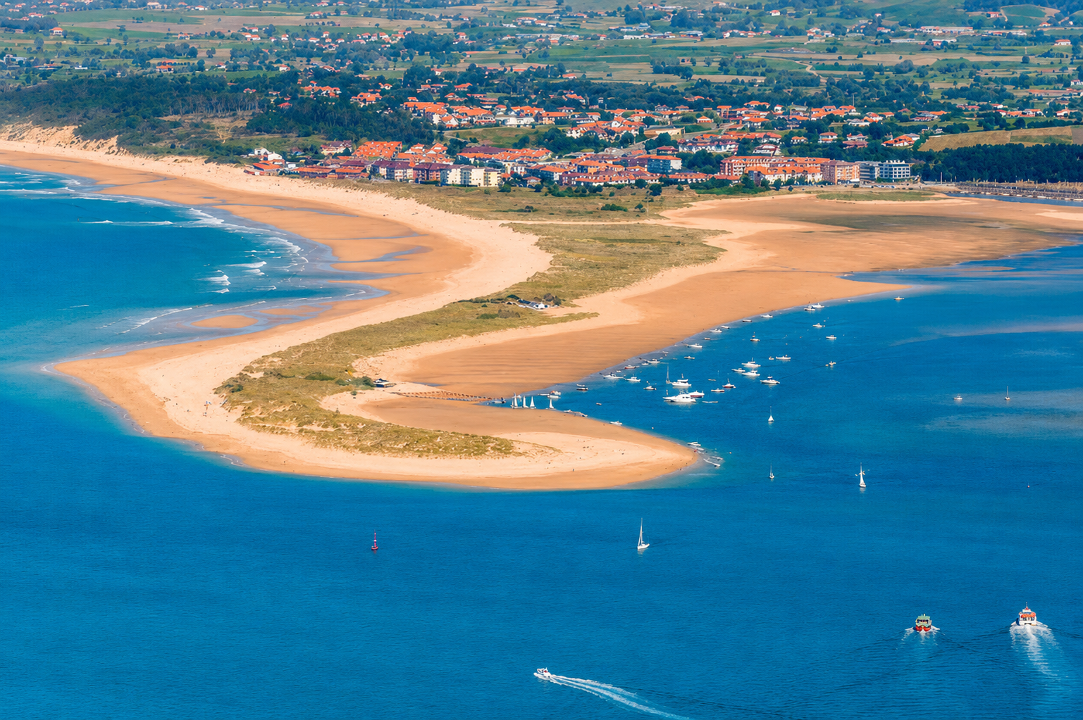 Vista aérea o desde la orilla de la Playa del Puntal en Somo, mostrando la lengua de arena entre la bahía de Santander y el mar Cantábrico