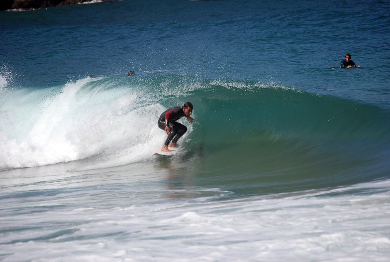 Surfistas principiantes con tabla entrando al agua en la playa de Cuberris (playa de Ajo), Bareyo, día soleado