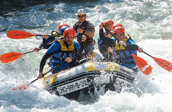 Grupo haciendo rafting o barranquismo en un río de aguas bravas