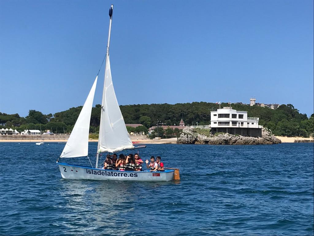 Velero de la escuela pública de vela en el islote de la Torre, bahía de Santander, atardecer