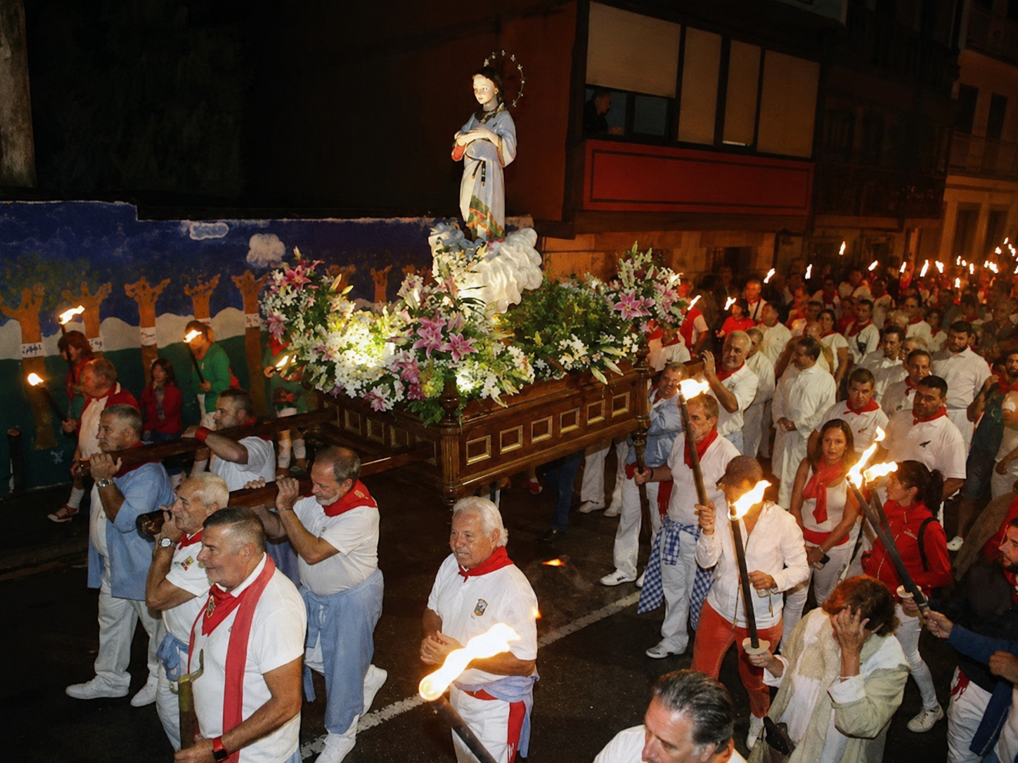 La Procesión de las Antorchas recorriendo de noche las calles de Ampuero la víspera del día grande, con la Virgen Niña a hombros entre antorchas.