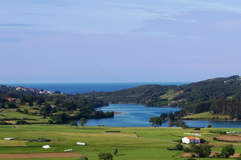 Vista general de la Ría de Ajo desde el sendero peatonal, marea baja, robledal cantábrico al fondo.
