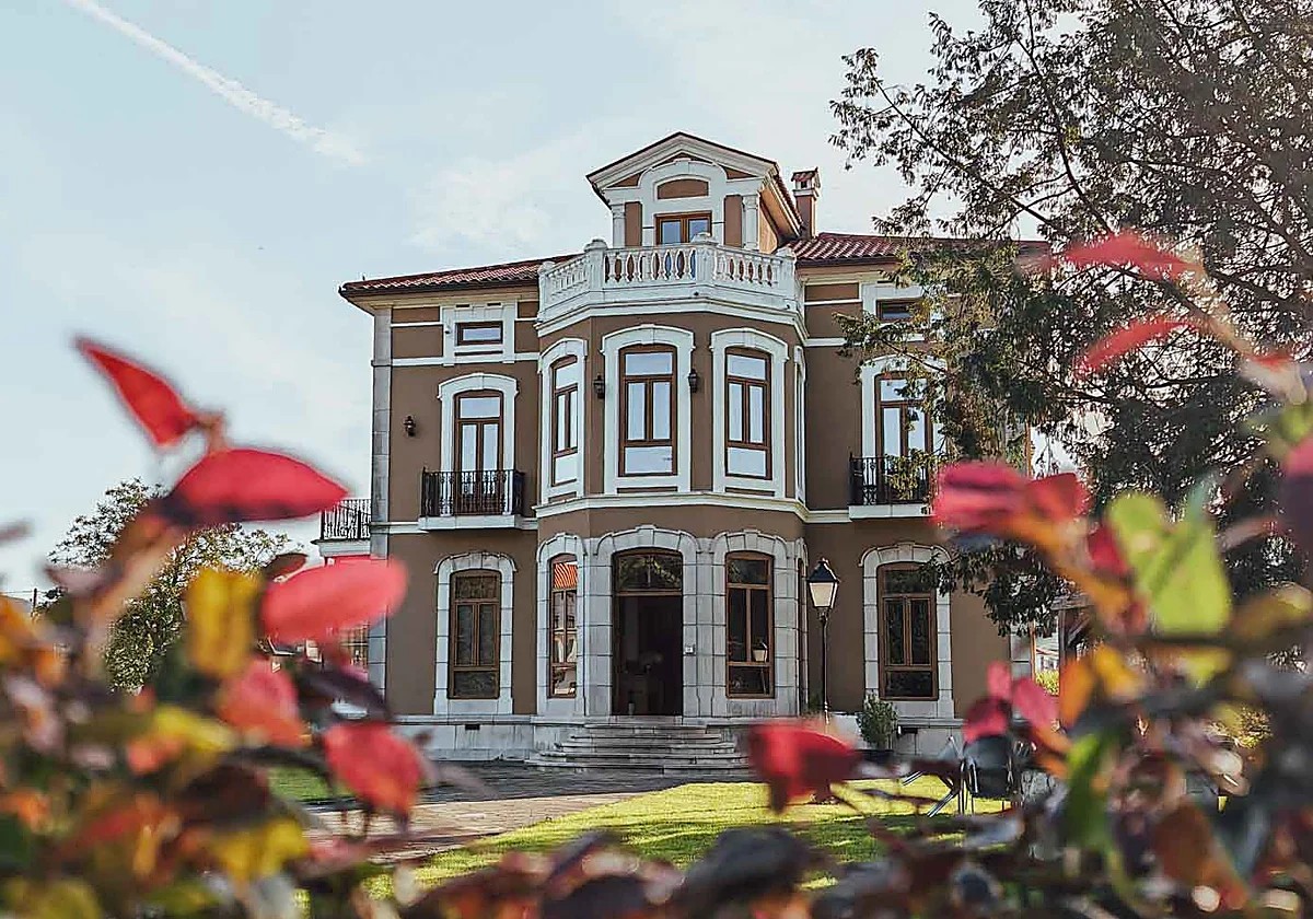 Fachada de una casona indiana cántabra con jardín y palmeras, vista exterior