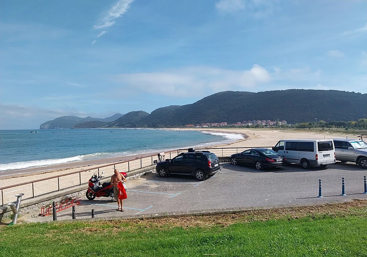 Aparcamiento de tierra junto a la playa de Berria en Santoña, con coches y la marisma protegida al fondo