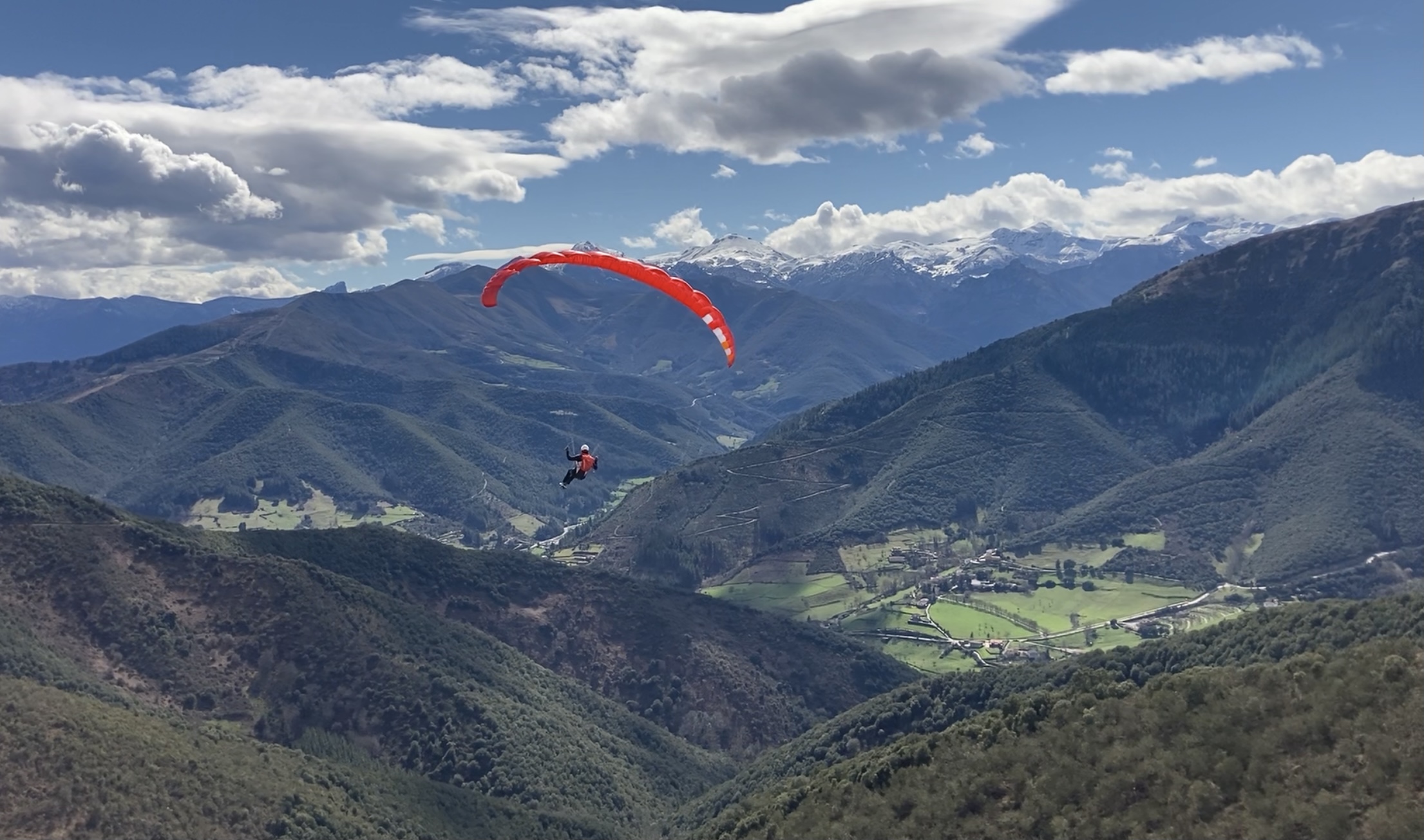 Parapente biplaza en el aire con los Picos de Europa de fondo, cerca de Potes