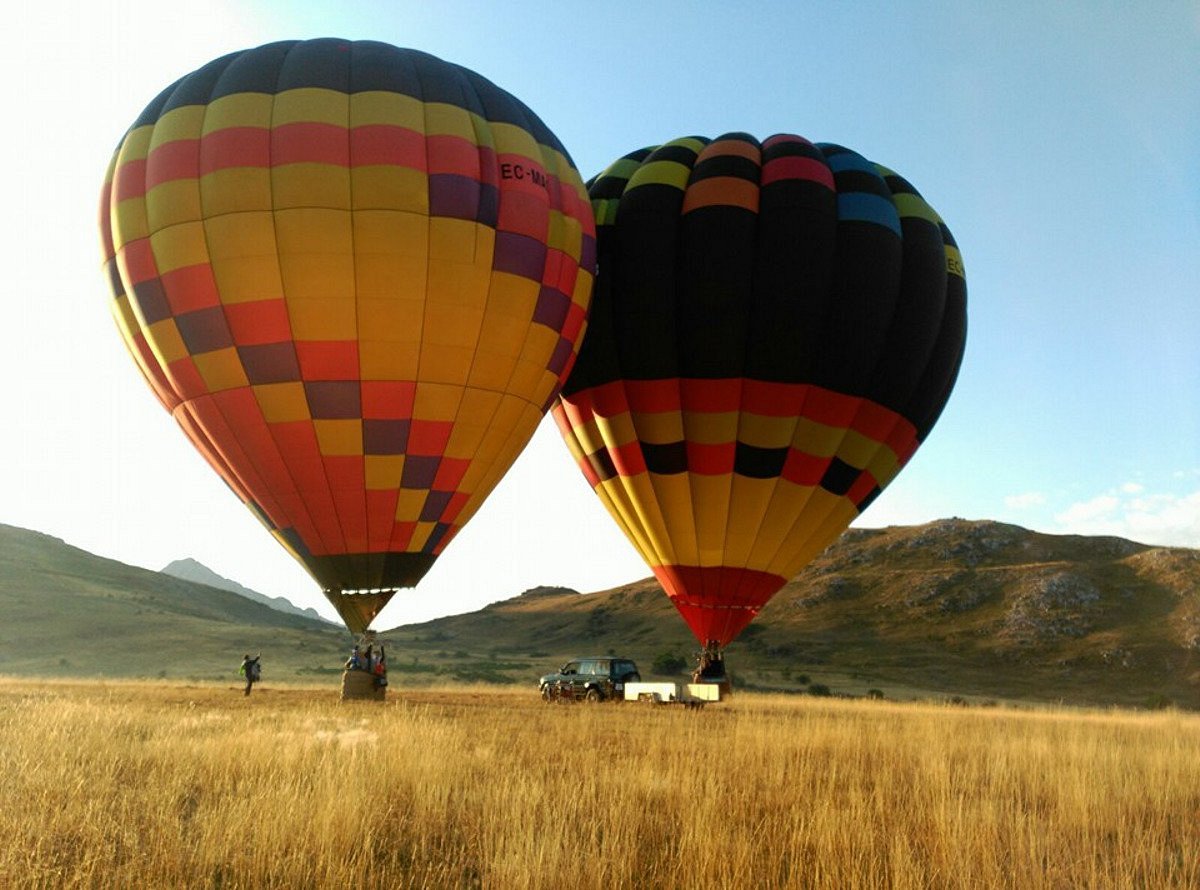 Globo aerostático de colores inflándose o despegando en un prado de los Valles Pasiegos al amanecer